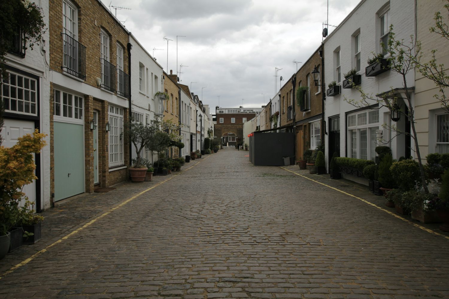 A cobbled London street lined with brick buildings